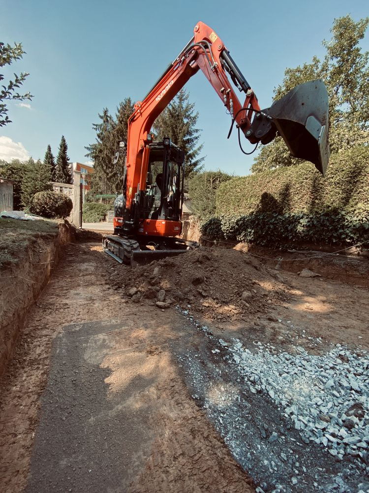 Široký výkop mezi živými ploty připravený k&nbsp;zásypu kamenivem