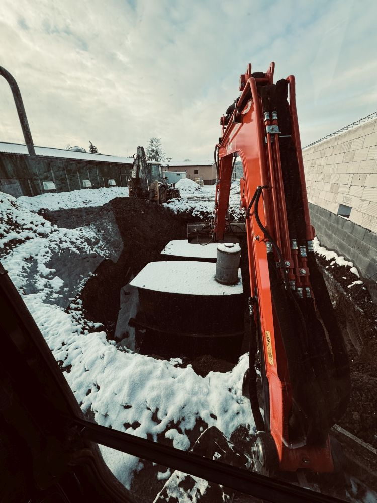 Osazování betonových nádrží do výkopu na zasněženém staveništi