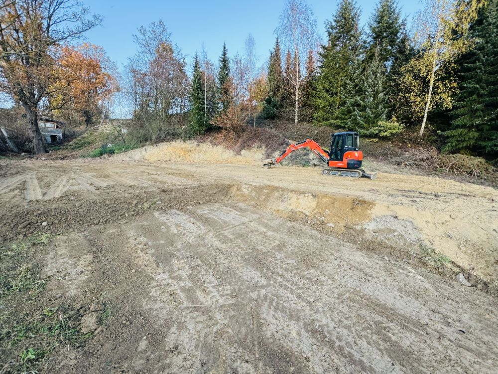 Srovnaná plocha vyříznutá do svahu na okraji lesa